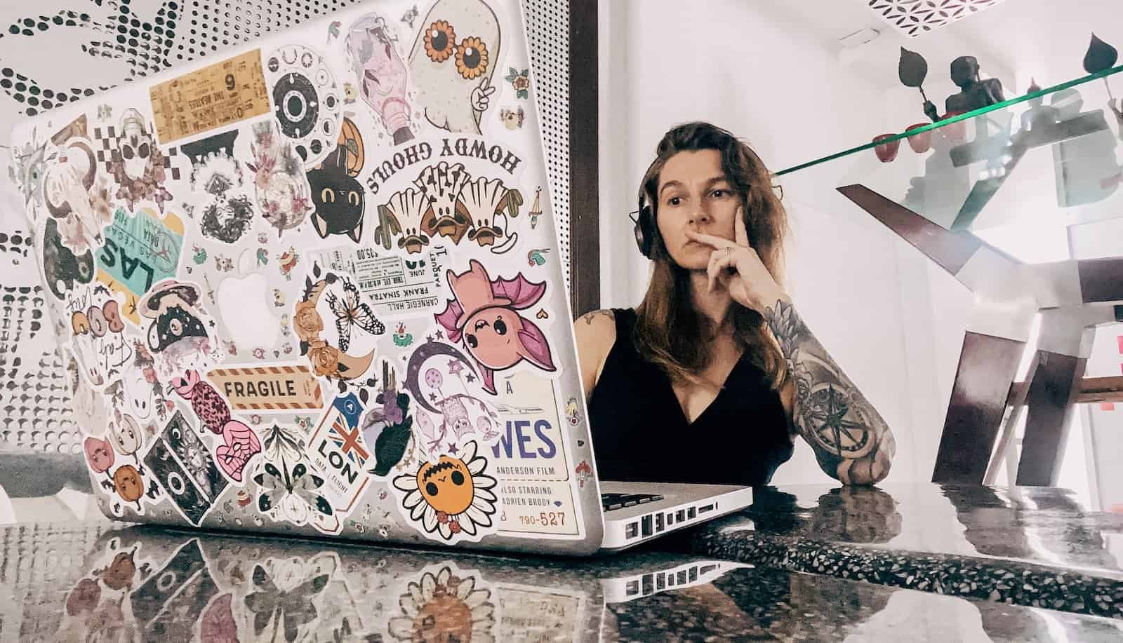 woman sat at sticker covered macbook laptop