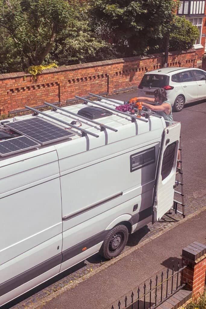 Man touching up rust on the roof of his converted campervan.