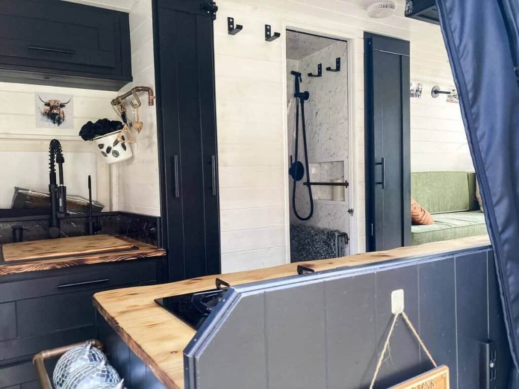 Luxury black and white interior of a Sprinter Van conversion and a full shower cubicle.