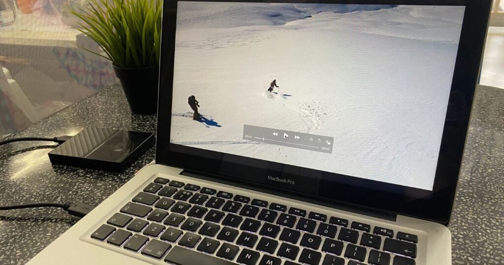 Laptop screen showing two skiers alone on the mountain.