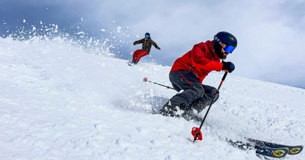 A close up of a skier in a red jacket blazing across the image with snow spraying up behind him. During a winter vanlife trip to the Norwegian mountains. 