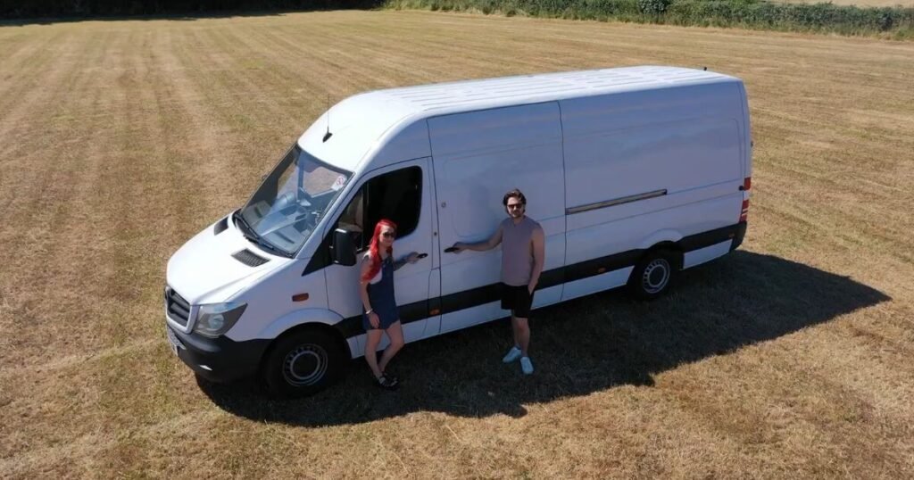 Two people stood in front of a Mercedes Sprinter panel van in a large field in spring 