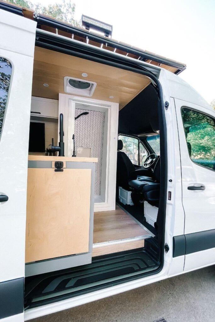 A converted van shower behind the drivers seat of a Mercedes Sprinter.