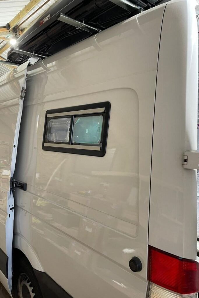 A close up of a small rectangular window in the side of a white van 