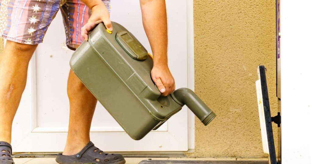 Emptying the removeable waste container for a chemical camper van toilet at an official dumping site 