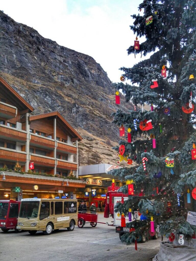 Zermatt town square Christmas tree and electro vehicles at the train station.