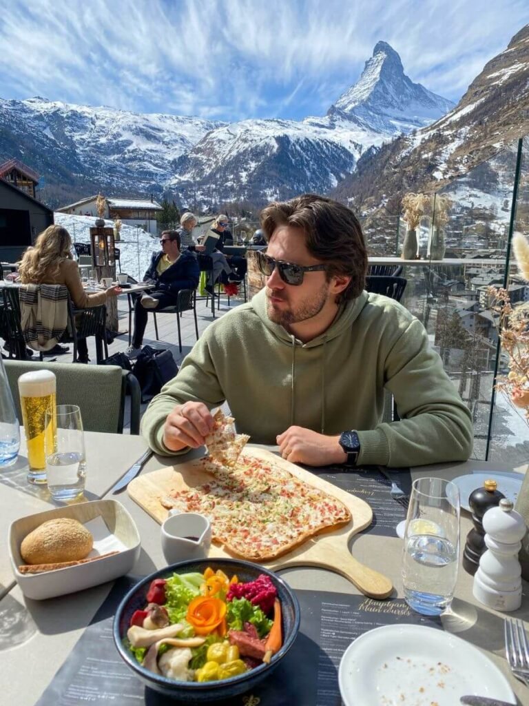 A Man eating a flatbread at Chalet Schönegg, in front of the Matterhorn.