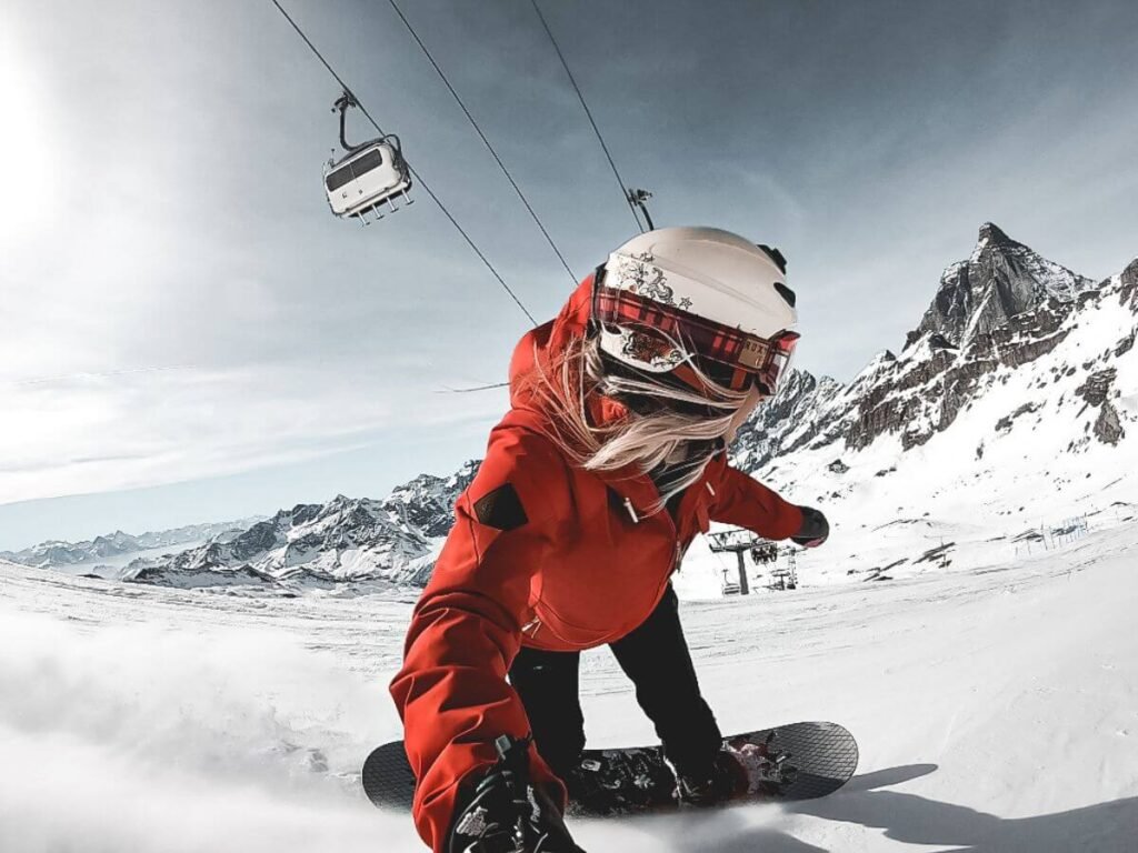 Woman in red jacket snowboarding in Cervinia, underneath Cervino (The Matterhorn).