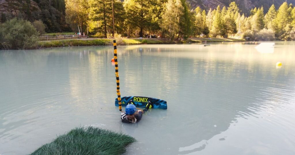 A girl sitting ready to take off wakeboarding at Shalisee Lake, Täsch.